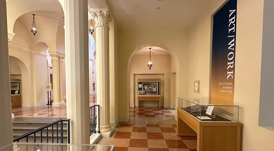 Colonnade in library with exhibit cases on the perimeter.