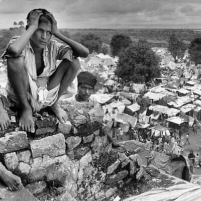 A youth sits on the wall of the Purana Qila fortress in New Delhi that overlooks thousands of dispossessed Muslims who had fled their homes from terror.