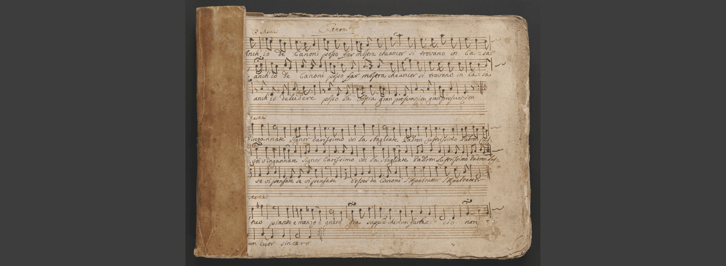 Music manuscript pages bound together showing leather binding at the left edge.