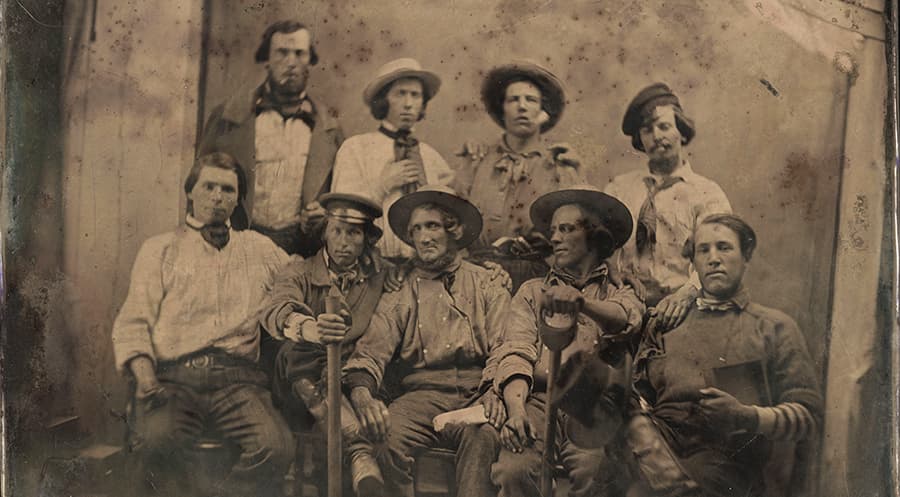 An old photograph of a group of miners from around 1849 posing in front of a camera.
