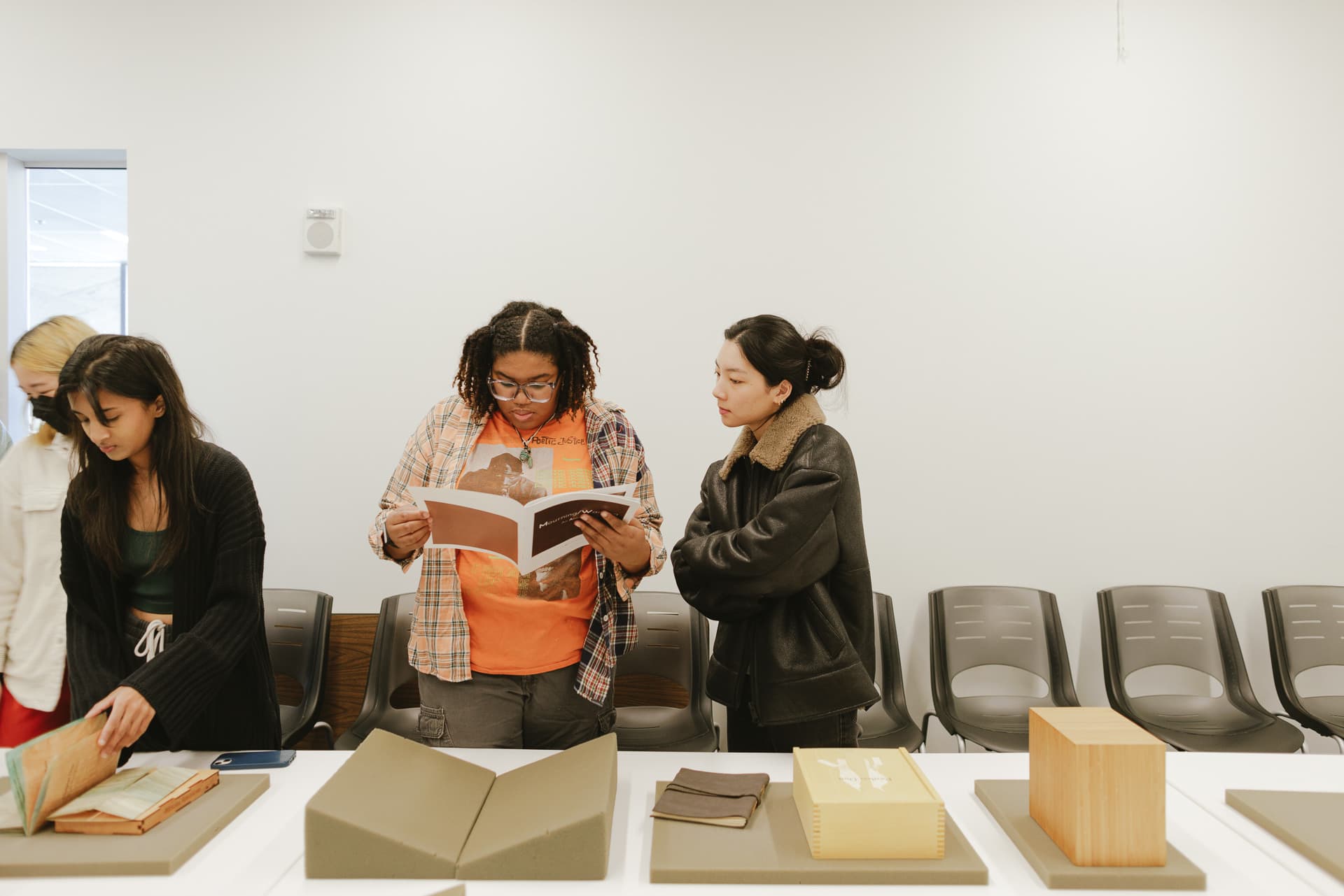 Four students looking through manuscripts that are on display on a table.